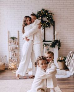 two children in white outfits are sitting on the floor with their arms around each other