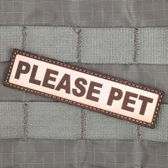 a sign that says please pet on the back of a suit jacket with brown stitching