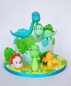 a birthday cake decorated with dinosaurs and plants