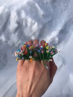 a hand holding some flowers in the snow