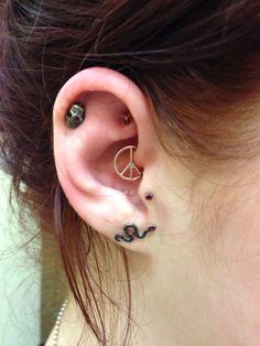 a woman with two piercings on her ear and one behind the ear is a snake