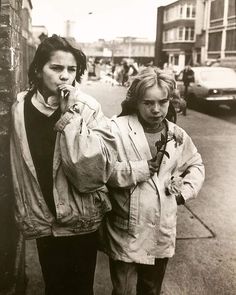 black and white photograph of two people walking down the street talking on their cell phones