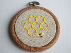 a close up of a embroidery on a wooden frame with a bee and honeycomb