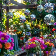 several vases filled with flowers and disco balls hanging from the ceiling in a garden