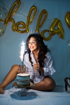 a woman sitting in front of a cake with sparklers