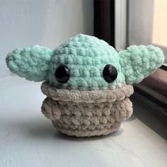 a crocheted yoda toy sitting on top of a window sill