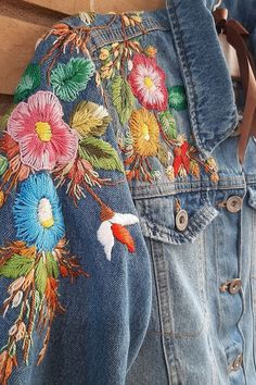 a pair of jeans with embroidered flowers on them and a purse hanging from the back