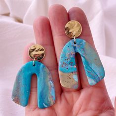 Blending the beauty of turquoise waters with sandy beaches. These arch earrings are the perfect size to for a beach outfit or pair with anything. Available in blue and sand with speckled designs. A must-have for every beach enthusiast.  Our turquoise Waters Earrings are handcrafted in polymer clay and fired to create a beautiful piece that will last for years. The lightweight design adds a mix of fun and funk, with a twist. SPECS: Do you want to stand out from the crowd?  Wear these fun animal e Blue Resin Jewelry For Summer, Blue Dangle Earrings With Ocean-inspired Style, Ocean-inspired Blue Dangle Earrings, Ocean-inspired Blue Earrings With Ear Wire, Turquoise Resin Drop Earrings, Artsy Turquoise Nickel-free Earrings, Artsy Nickel-free Turquoise Earrings, Blue Dangle Earrings For The Beach, Unique Blue Summer Jewelry