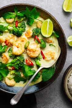 a bowl filled with shrimp, broccoli and rice next to lime wedges