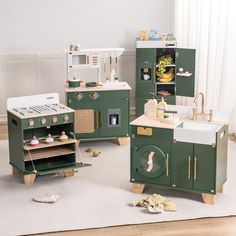 an assortment of green play kitchen sets in a child's playroom with white walls