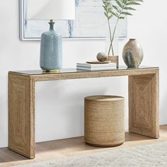 a console table with two vases and a plant on it in front of a painting