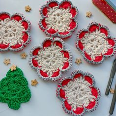 four crocheted christmas ornaments sitting on top of a table next to a pair of scissors