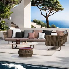 an outdoor living area with couches and tables next to a swimming pool in front of a house