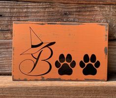 an orange sign with black paw prints and a witch's hat on the top