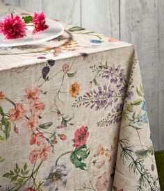 the table cloth has flowers on it and is next to a plate with a pink flower