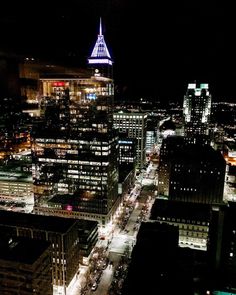 an aerial view of a city at night with cars driving on the street and buildings lit up