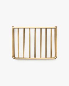 a gold metal belt buckle with bars on it, against a white background the clasp is made out of thin brass wire