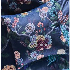 two blue pillows with colorful flowers on them sitting next to each other in front of a pillow case