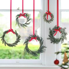 three wreaths hanging from the window with red ribbon