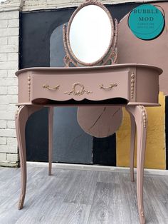 a pink vanity table with a mirror on it and a brick wall in the background