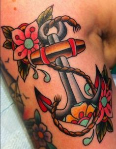 an anchor tattoo with flowers on it