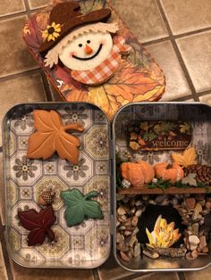 two tins filled with different types of fall decorations