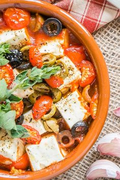 an orange bowl filled with vegetables and tofu on top of a red checkered table cloth