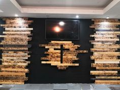 a black wall with wooden planks and a television mounted to it's side