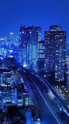 an aerial view of a city at night with lots of tall buildings in the foreground