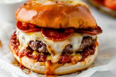 a cheeseburger with pepperoni, meat and melted cheese on it's bun