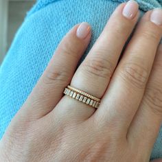 a woman's hand with a gold ring on top of her finger and a diamond band in the middle