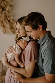 a man and woman holding a baby in their arms