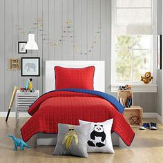 a child's bedroom with red and blue bedding, white walls and wooden floors