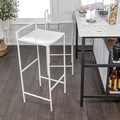 two white bar stools sitting on top of a wooden floor next to a counter