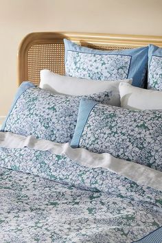 a bed with blue and white comforters on top of it in front of a beige headboard