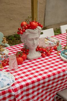 a table topped with plates and bowls filled with tomatoes on top of a checkered table cloth