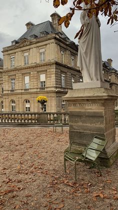 there is a bench in front of a building with a statue on the ground next to it