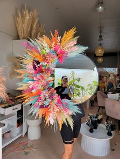 a woman taking a selfie in front of a mirror with colorful flowers on it