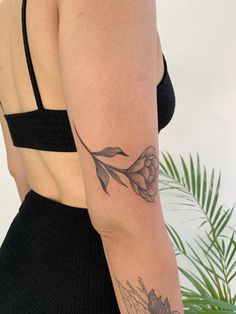 a woman with a flower tattoo on her left arm and right arm behind her back