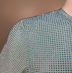 the back of a woman's dress with blue and green dots on it, in front of a mannequin head