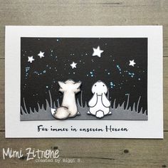 a card with two dogs sitting on the ground in front of stars and night sky