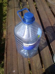 a large plastic water bottle sitting on top of a wooden bench next to a can