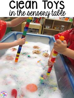 two children are playing with toys in a play table filled with foam and sand that says, clean toys in the sensory table