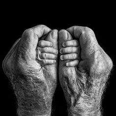 an old man's hands holding something in front of his face, black and white photograph