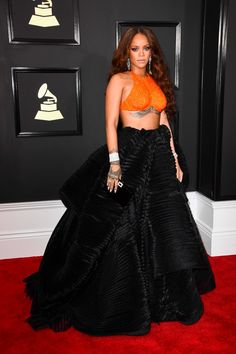 a woman in an orange crop top and black skirt on the red carpet at awards