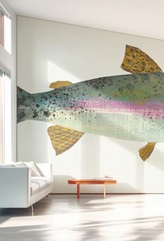 a large fish painted on the wall next to a couch and coffee table in a living room