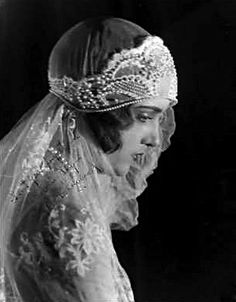 an old black and white photo of a woman wearing a veil