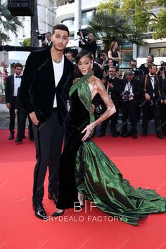 a man and woman standing on top of a red carpet next to eachother