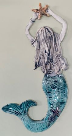 a ceramic sculpture of a mermaid holding a starfish