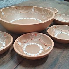 four bowls with designs on them sitting on a table top next to two plates and one bowl